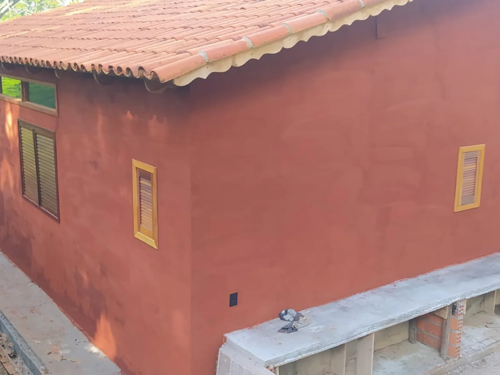 Casa de campo com pintura em tom terracota e acabamento em massa