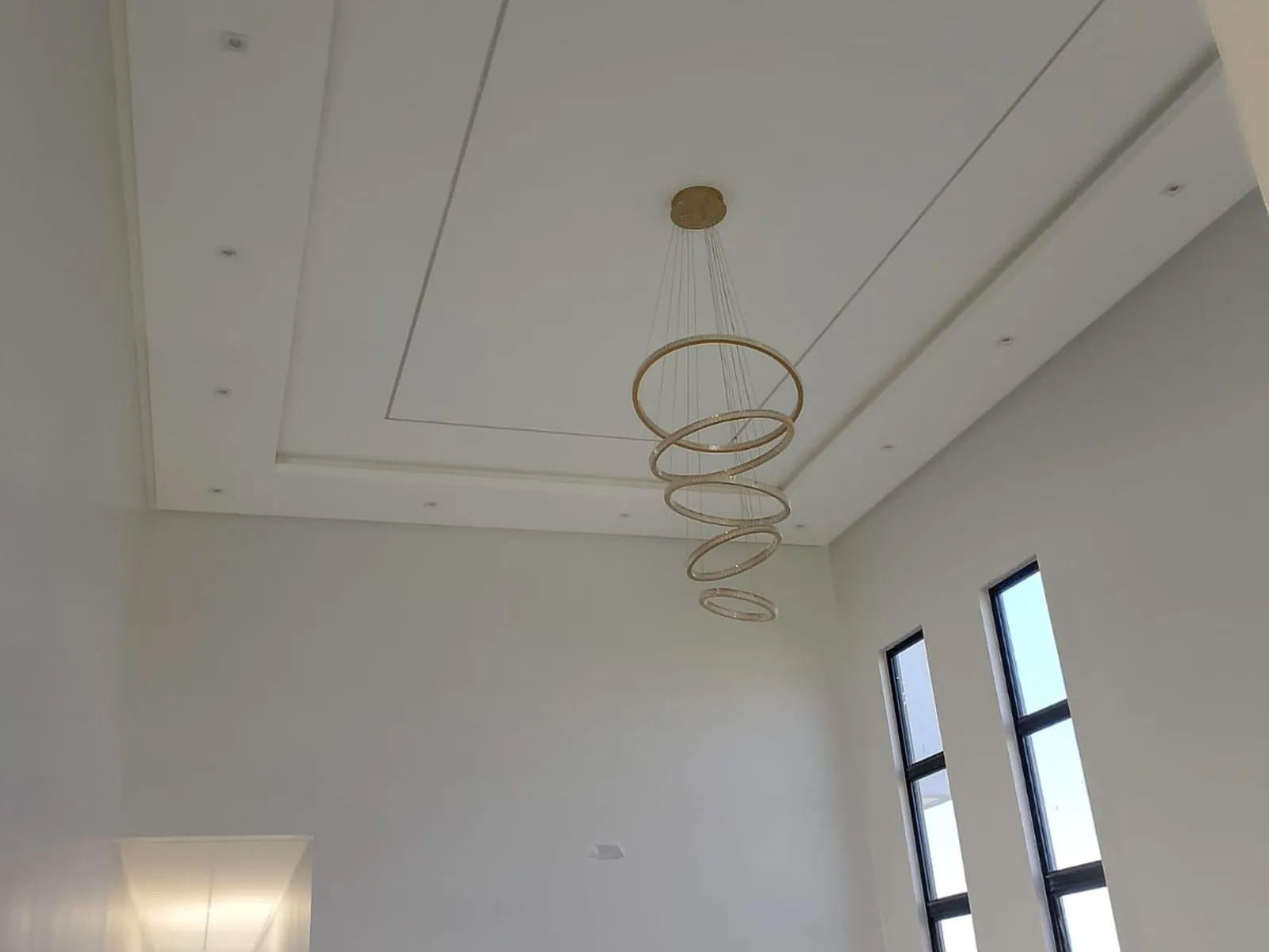 Ambiente com pé-direito alto, sanca de gesso e acabamento branco impecável